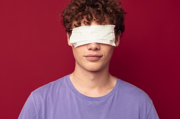 Foto protección de máscara médica de chico joven posando fondo rojo inalterado