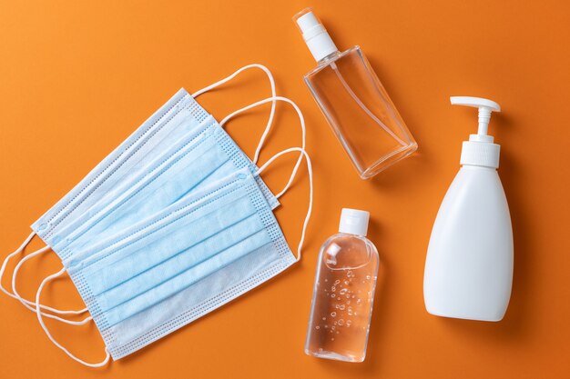 Protección médica, mascarillas, gel desinfectante, spray, jabón líquido para manos sobre fondo naranja