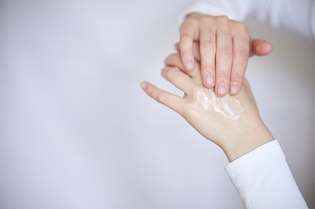 protección de la piel de las manos en la estación fría Primer plano de una mujer aplicándole crema