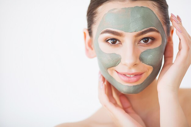 Protección de la piel. Mujer joven con máscara de arcilla cosmética con pepino en su baño