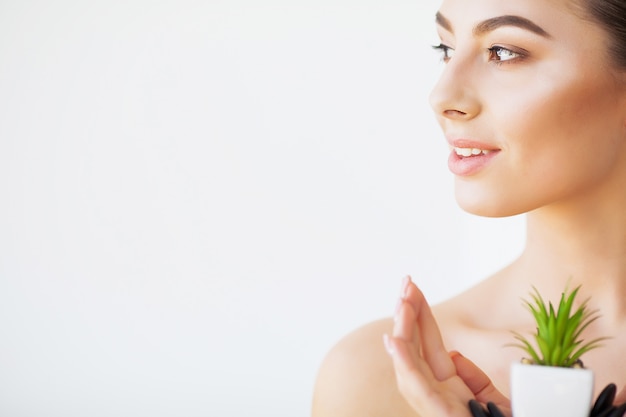 Protección de la piel. Rostro de mujer de belleza con piel sana y planta verde