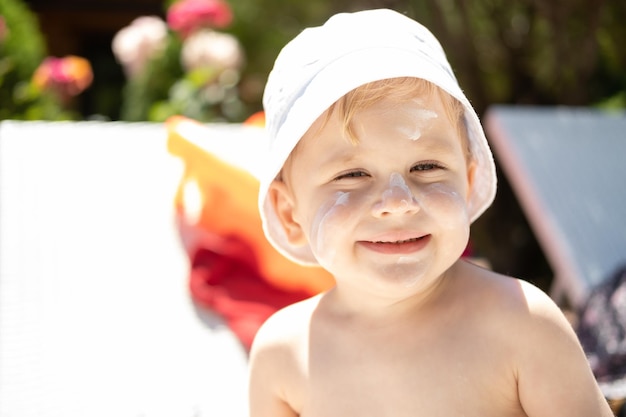 Protección solar de cerca el retrato de la cara del niño sonriente con protector solar