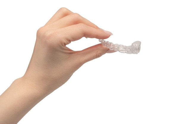 Protector bucal transparente en la mano de una mujer aislado sobre un fondo blanco