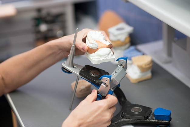 Prótese dentária. Protetista trabalhando com equipamentos na clínica odontológica