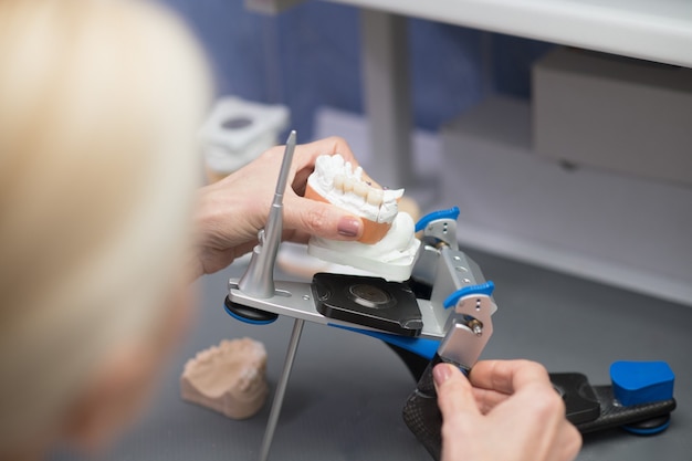 Foto prótese dentária. protetista trabalhando com equipamentos na clínica odontológica