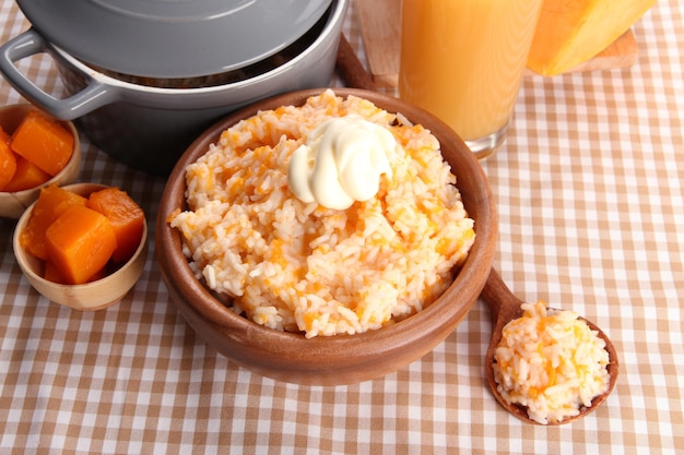 Prove mingau de arroz com abóbora e copo de suco no fundo da toalha de mesa