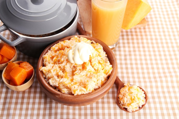 Prove mingau de arroz com abóbora e copo de suco no fundo da toalha de mesa