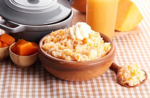 Prove mingau de arroz com abóbora e copo de suco no fundo da toalha de mesa