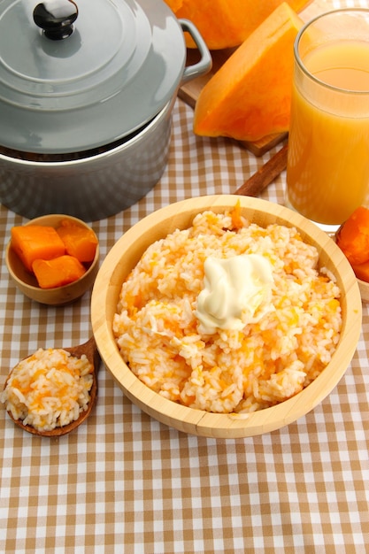 Prove mingau de arroz com abóbora e copo de suco no fundo da toalha de mesa