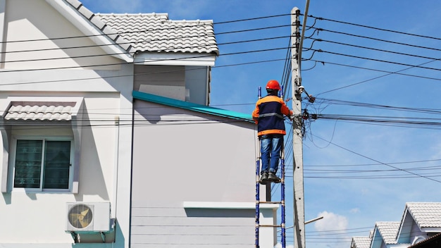 El proveedor técnico de servicios de Internet está revisando los cables de fibra óptica después de instalarlos en un poste eléctrico