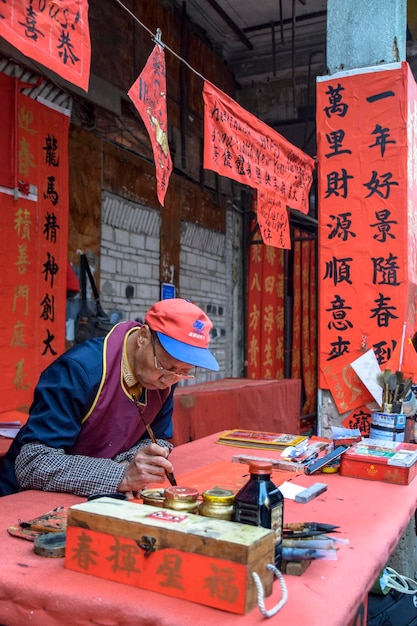 Província de Foshan Guangdong China 14 de janeiro de 2022 Pessoas escrevendo dísticos com saudações para o Festival da Primavera Preparação para a celebração do Ano Novo Chinês na rua Kuaizi em Foshan