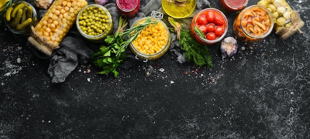 Provisiones de alimentos en frascos de vidrio verduras en vinagre sobre un fondo negro Vista superior