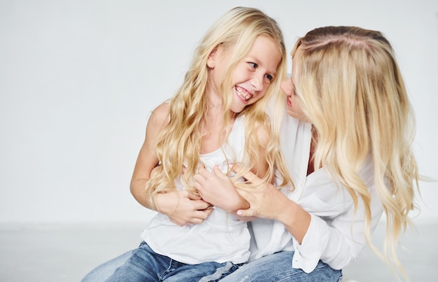 Proximidade das pessoas. Mãe com a filha junto no estúdio com fundo branco.