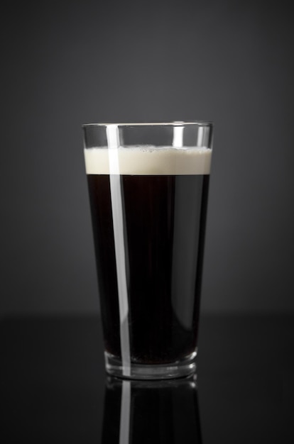 Foto proyecto de nitrógeno fresco y cremoso pinta de cerveza negra sobre fondo negro