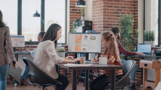 Proyecto de planificación de la madre trabajadora y niña garabateando en el portátil en el lugar de trabajo. Mujer de negocios trabajando en equipo para diseñar una nueva estrategia mientras tiene hija en la oficina de trabajo.