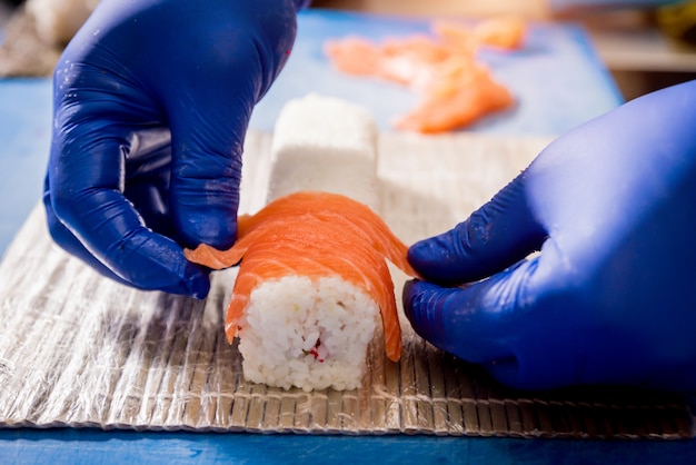 Prozess der Herstellung von Sushi und Brötchen in der Restaurantküche. Köche Hände mit Messer.