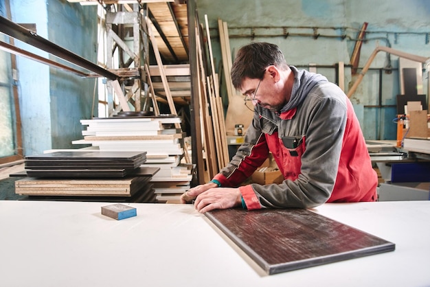 Prozess der Produktion und Herstellung von Holzmöbeln in der Möbelfabrik Arbeiter Zimmermann im Overall verarbeitet Holz auf Spezialgeräten