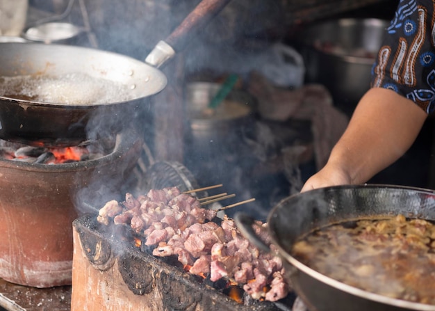 Prozess des grillens und zubereitens traditioneller speisen von sate klatak aus yogyakarta, einem lamm-satay.