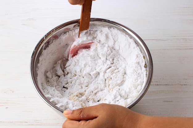 Prozess Kochen oder Backen Asiatische weibliche Hand Mischen Sie Tapiokamehl in der Edelstahlschüssel mit einem Silikonspatel