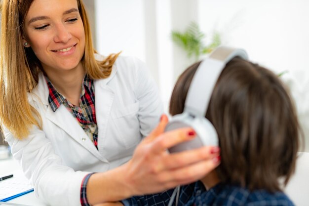 Foto prueba de audición para niños audiólogo trabajando con un niño pequeño.