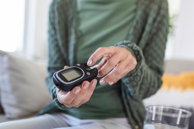 Prueba de azúcar en sangre en casa. Comprobación del nivel de azúcar en sangre en casa. Control de los niveles de azúcar en sangre para diabéticos. Mujer comprobando el nivel de azúcar en sangre con glucómetro y banda de prueba en casa