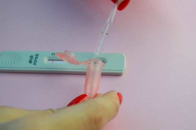 Prueba de coronavirus en un procedimiento médico de fondo rosa mate se gotea una solución salina