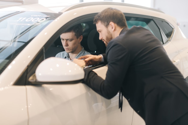 Prueba de joven guapo de coche nuevo en concesionario de automóviles