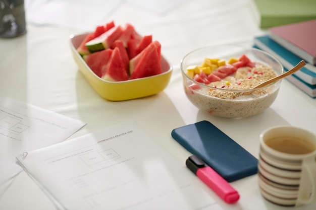 Pruebas de matemáticas junto a un tazón de avena y sandía cortada