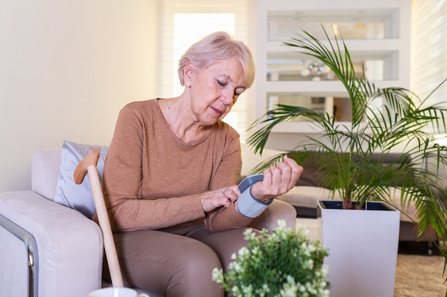 Pruebas de presión arterial en casa. Comprobación del nivel de presión arterial en el hogar. Senior mujer comprobando los niveles de presión arterial en casa