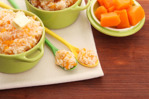 Pruebe las gachas de arroz con calabaza en cacerolas sobre fondo de madera