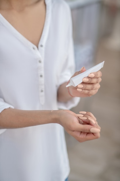 Prüfung, Pflegeprodukt. Nahaufnahme der weiblichen Hände und des kosmetischen Produkts am Handgelenk und im Schlauch, Gesicht nicht sichtbar