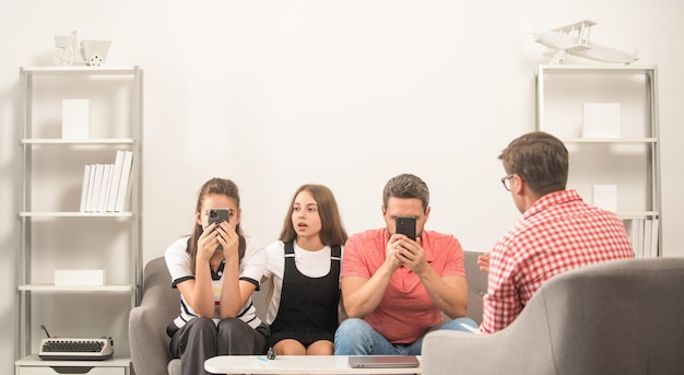 Foto el psicólogo da terapia familiar para el padre adicto al teléfono, la madre y la hija, la relación.