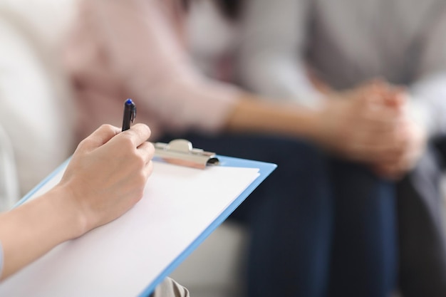 Psicólogo escribiendo en el bloc de notas en blanco, pareja reconciliándose en sesión de terapia en la oficina de psicoterapeutas, espacio de copia