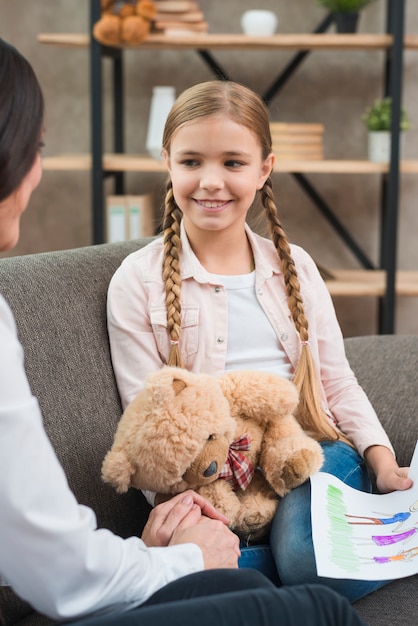 Psicólogo feminino reconfortante sorridente menina durante a sessão de terapia