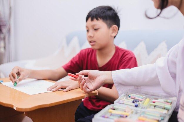 Psicólogo infantil hablando con un niño mientras dibuja en papel blanco Psicoterapia psicológica