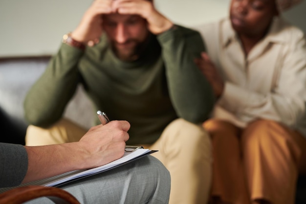 Foto psicólogo tomando notas durante la consulta con pareja