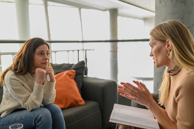 Psicoterapeuta explicando ansiedade chorando paciente feminina oferecendo apoio de tranquilização e orientação
