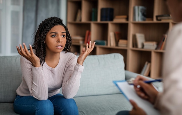 Psicoterapia Desesperada triste jovem negra emocional olhando para a médica europeia no escritório