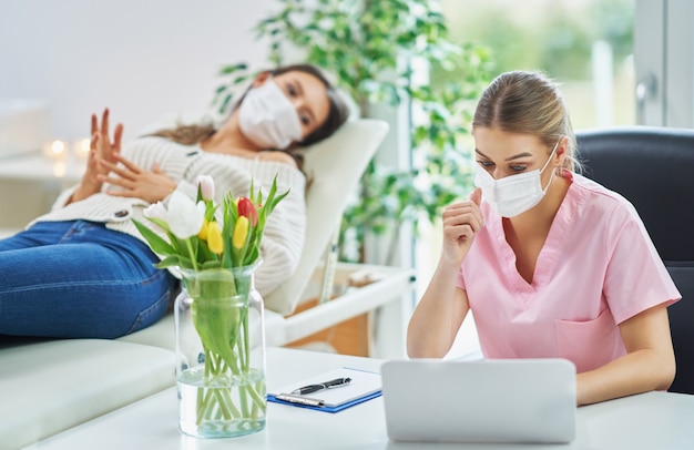 Foto psiquiatra profesional consultando a su paciente y tomando notas en máscaras