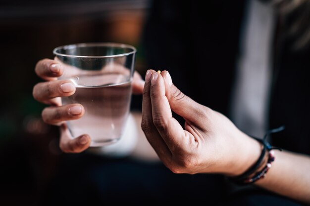 Foto psiquiatría - manos con píldora antidepresiva y un vaso de agua