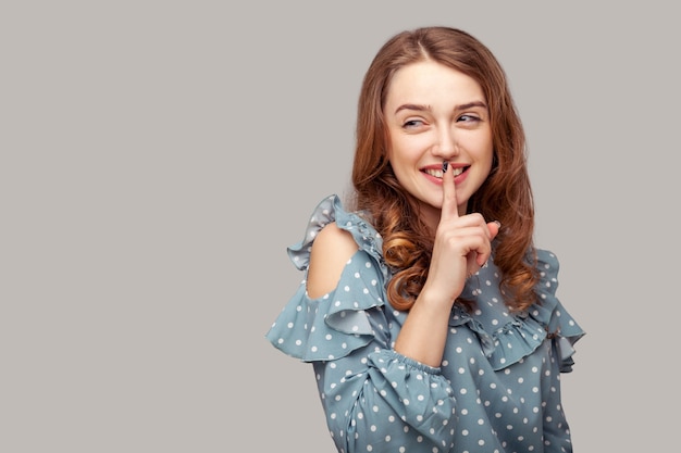 Pssst, bleib ruhig! Mädchen-Rüschenbluse, die mit dem Finger auf den Lippen um Stille bittet