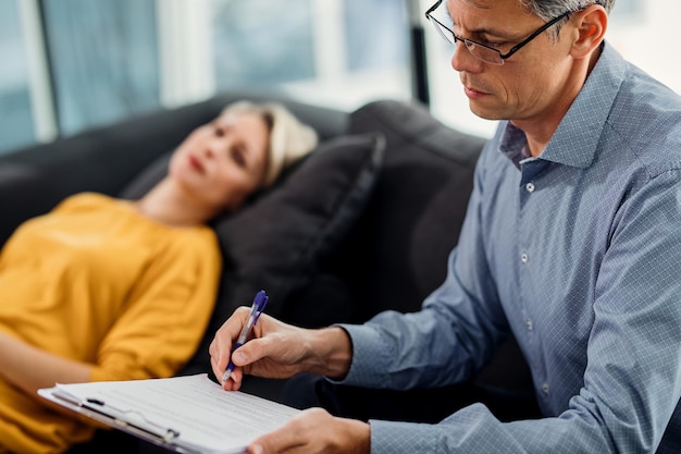 Psychiater, der Notizen macht, während er eine Therapiesitzung mit einem Patienten hat