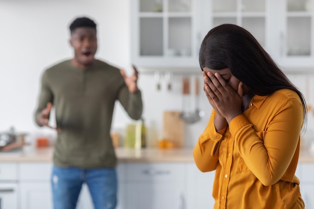 Psychische Gewalt, schwarze junge Frau, die das Gesicht bedeckt, während ihr Freund sie anschreit