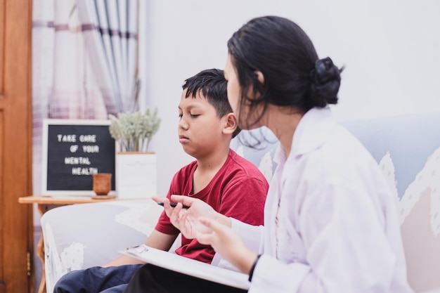 Psychologe, der mit einem traurigen Schuljungen in einem Büro arbeitet Psychische Gesundheitstherapie für Kinder