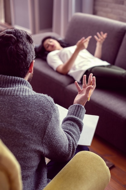 Foto psychologische therapie. schlauer netter mann, der seinem patienten die fragen stellt, während er eine psychologische therapiesitzung hat