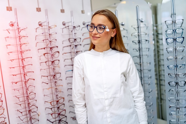 Óptica o clienta feliz está de pie con primas de gafas en la tienda óptica.