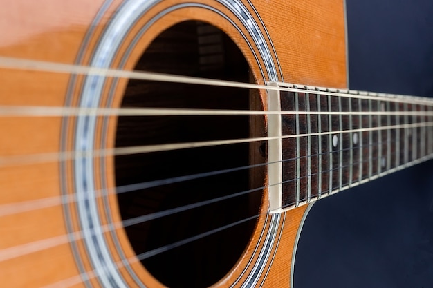 Púa de guitarra amarilla metida en cuerdas de guitarra acústica doradas