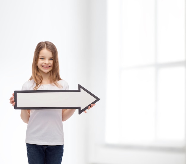 publicidad y concepto infantil - niña sonriente con flecha en blanco apuntando a la derecha