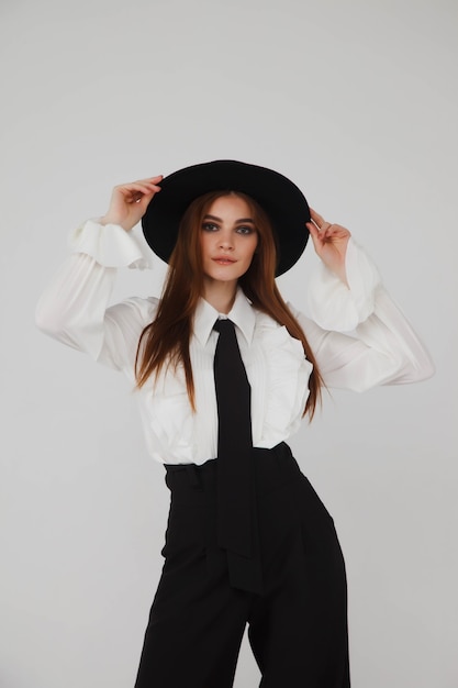 Publicidad elegante mujer joven linda en elegante blusa negra y sombrero