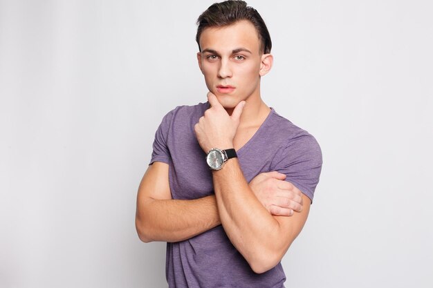 Foto publicidad y emoción de las personas hombre joven guapo en fondo gris mirando a la cámara retrato de joven riendo en bolsillos apoyado en la pared gris hombre feliz sonriendo